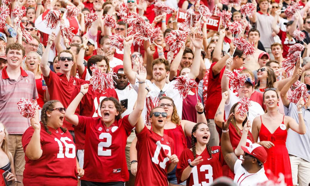 This image captures a sea of crimson and white fans standing together, which embodies the spirit behind Roll Tide — not just a phrase, but a fan identity.