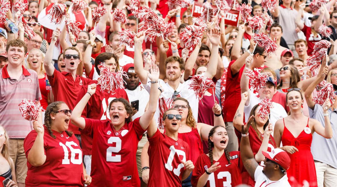 This image captures a sea of crimson and white fans standing together, which embodies the spirit behind Roll Tide — not just a phrase, but a fan identity.